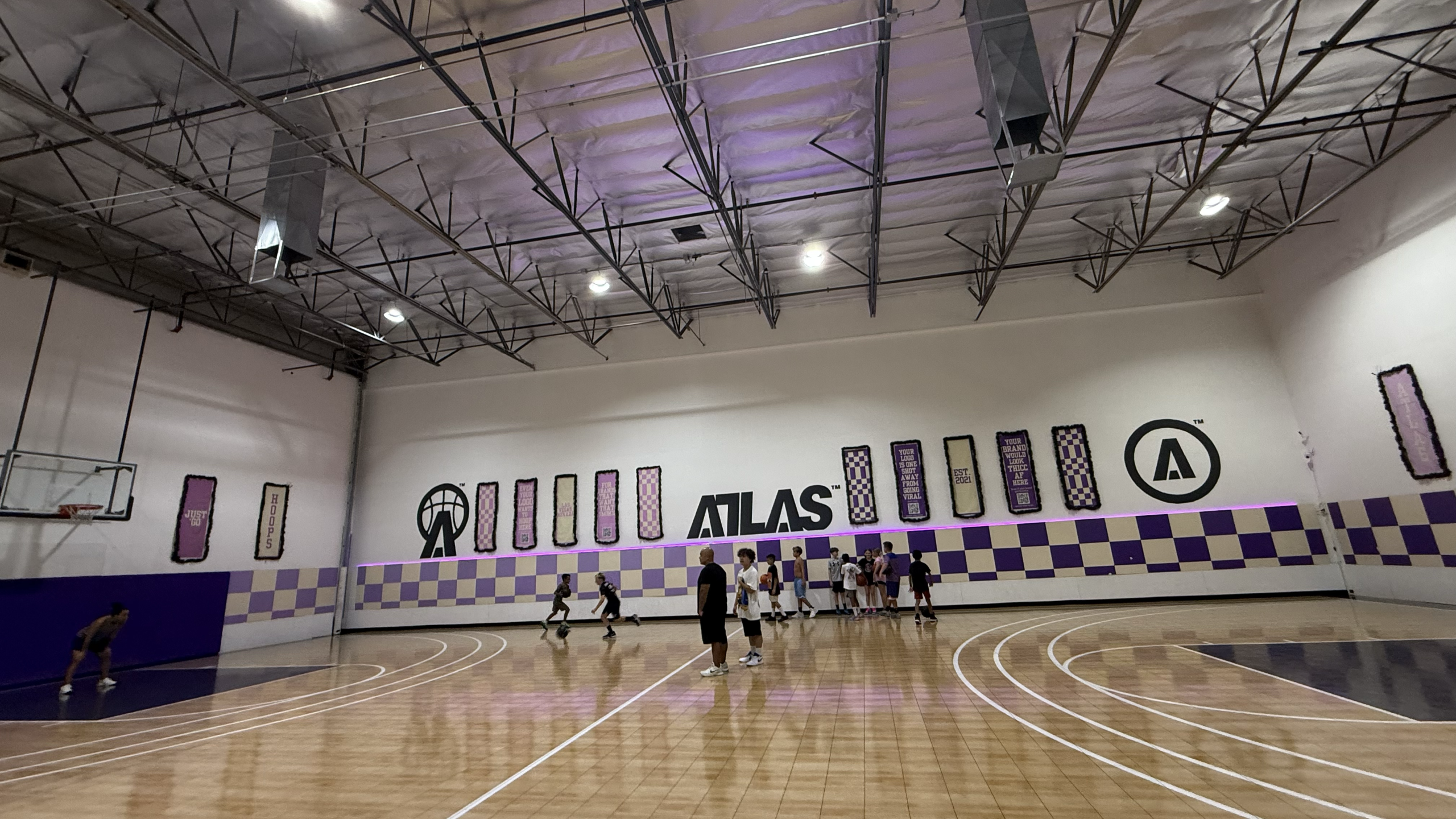 wide view of the ATLAS Hoops gym, banners and checkered wall